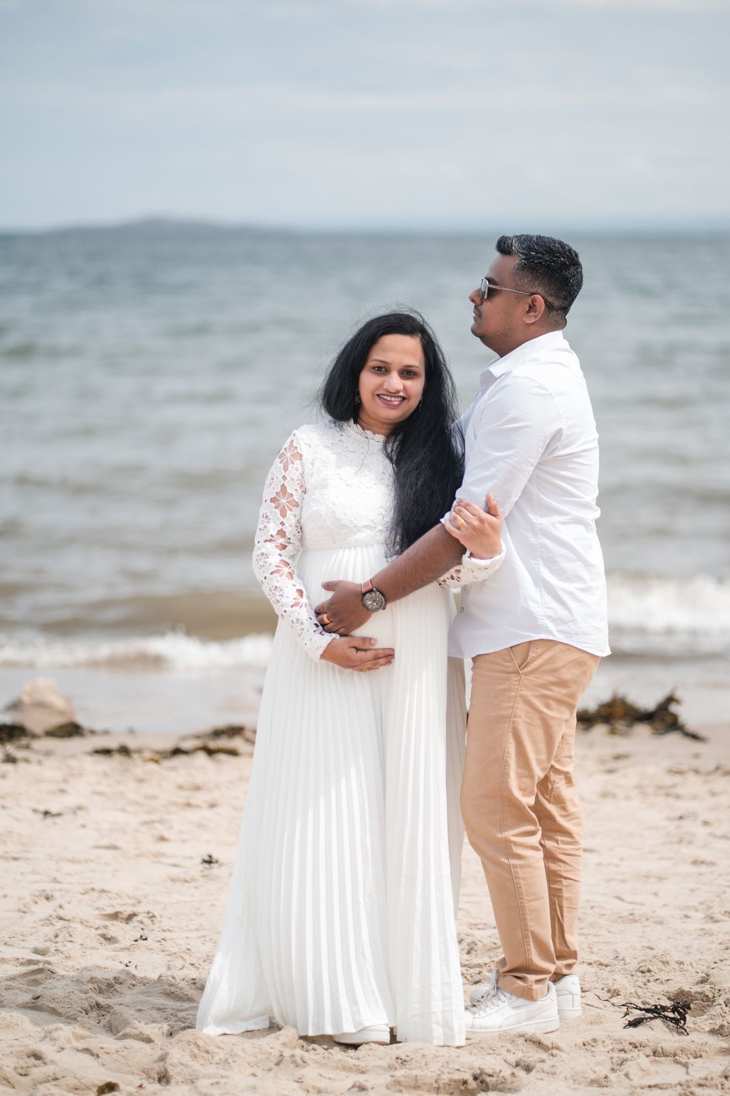 Expecting couple embracing on a beach
