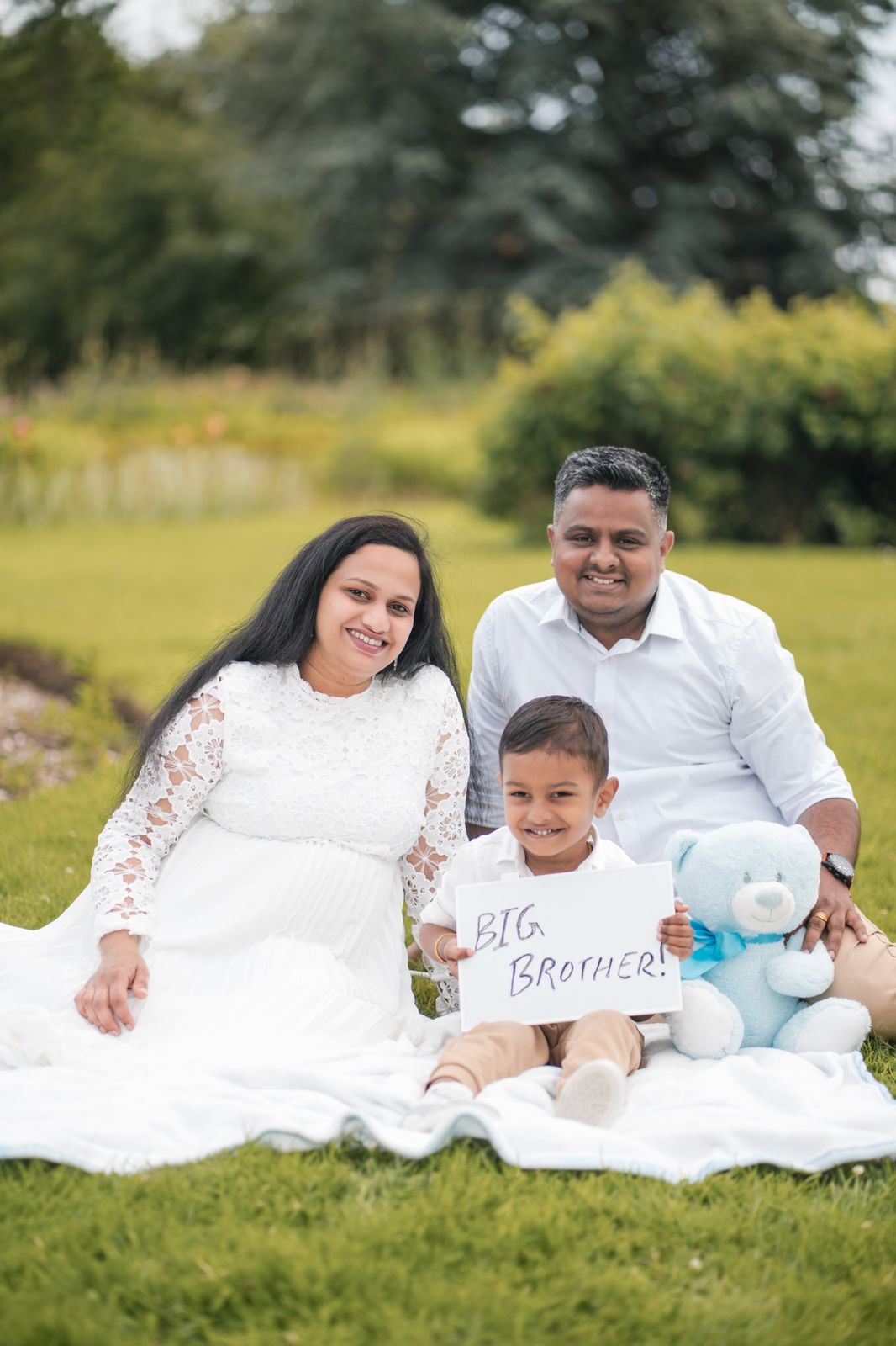 Family on a picnic blanket, son holding a Big Brother sign
